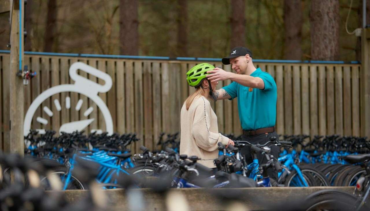 Cycle Centre employee helping a guest put on her helmet