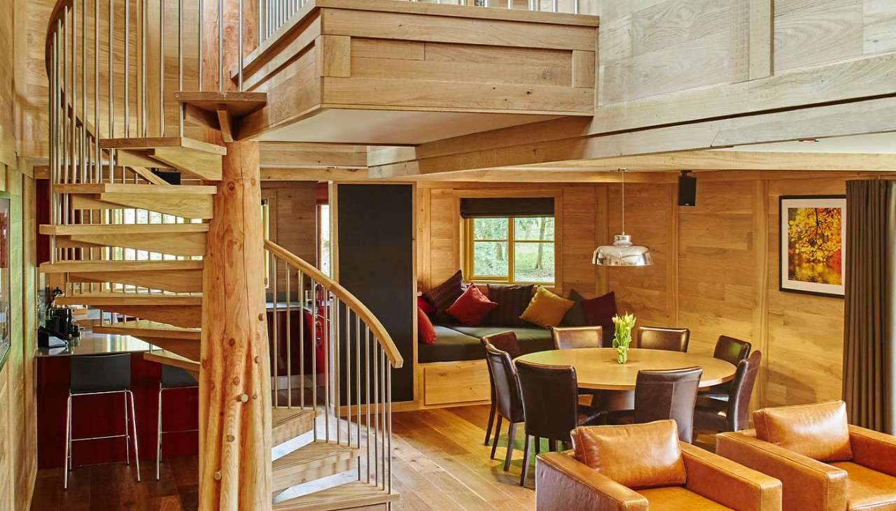 The living area and dining area inside a treehouse with a spiral staircase.