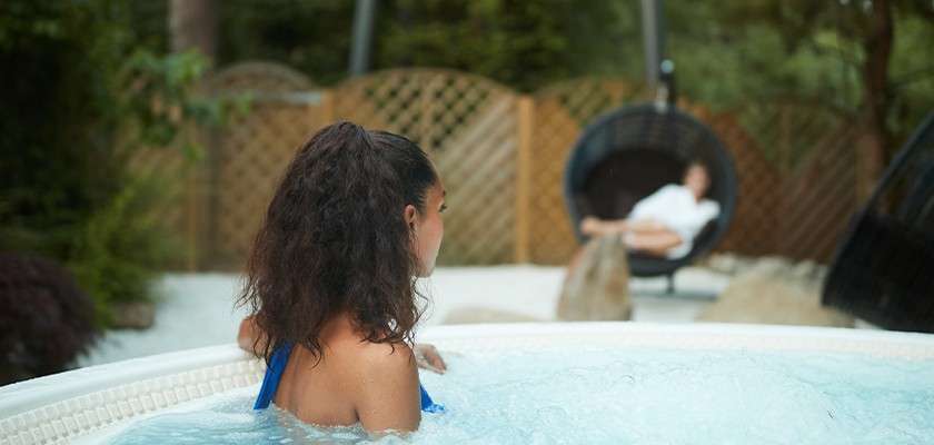 A woman relaxing in an outdoor hot tub.