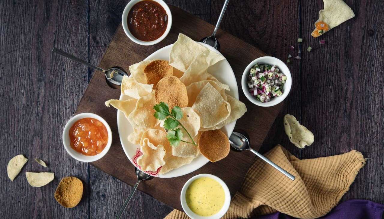 Plate with crispy poppadoms and flavourful dips.