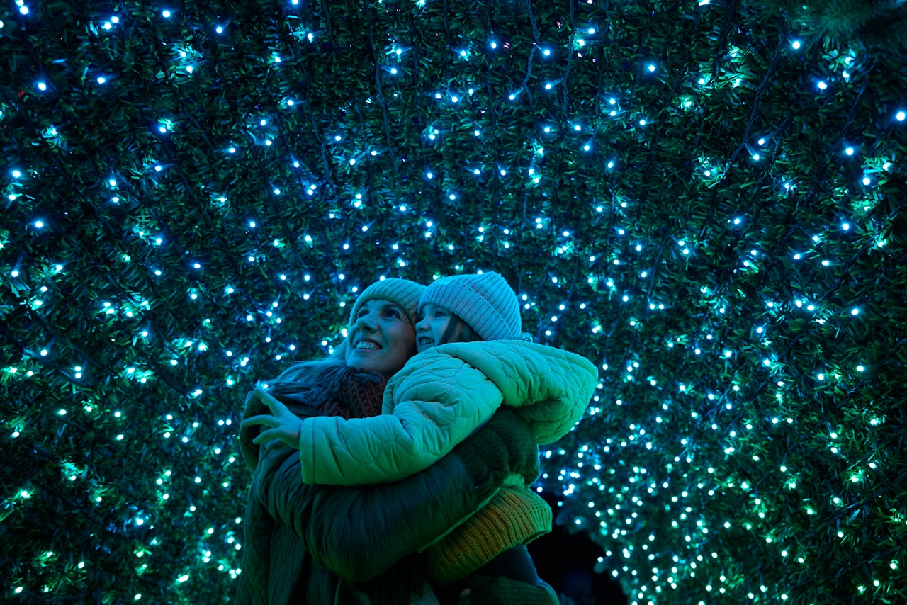 A brother and sister putting decorations on a christmas tree.
