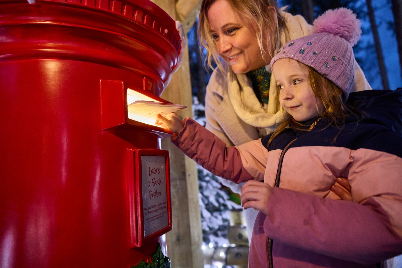 A girl posting a letter to Santa through a post box.