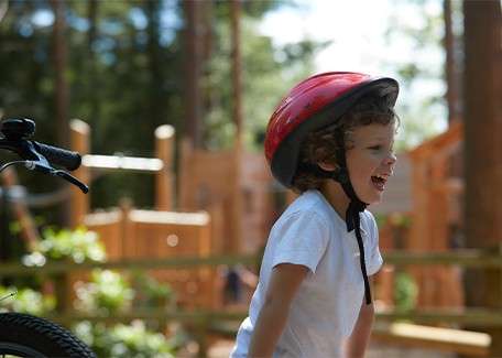 A teenage girl looking over her shoulder and smiling down at her parents whilst she climbs the indoor climbing wall.