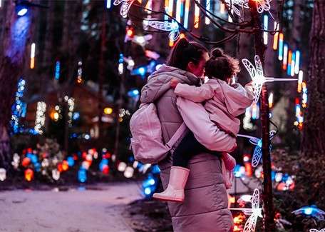 A mother and daughter looking at the lights in the forest.