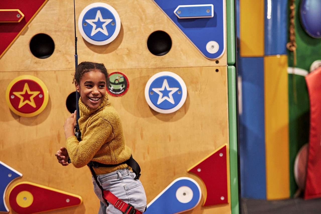 a girl smiling on a climbing wall