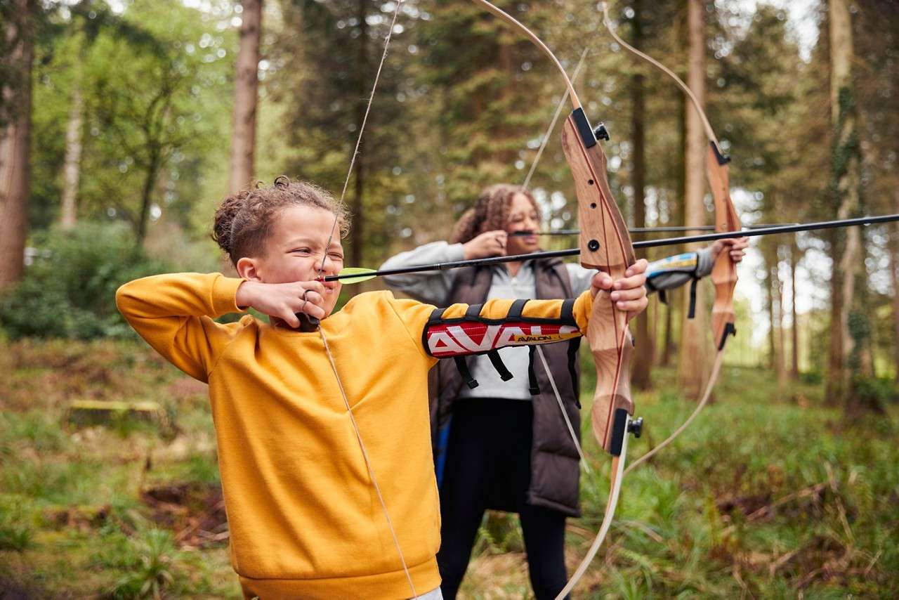 Brother and sister doing archery together.