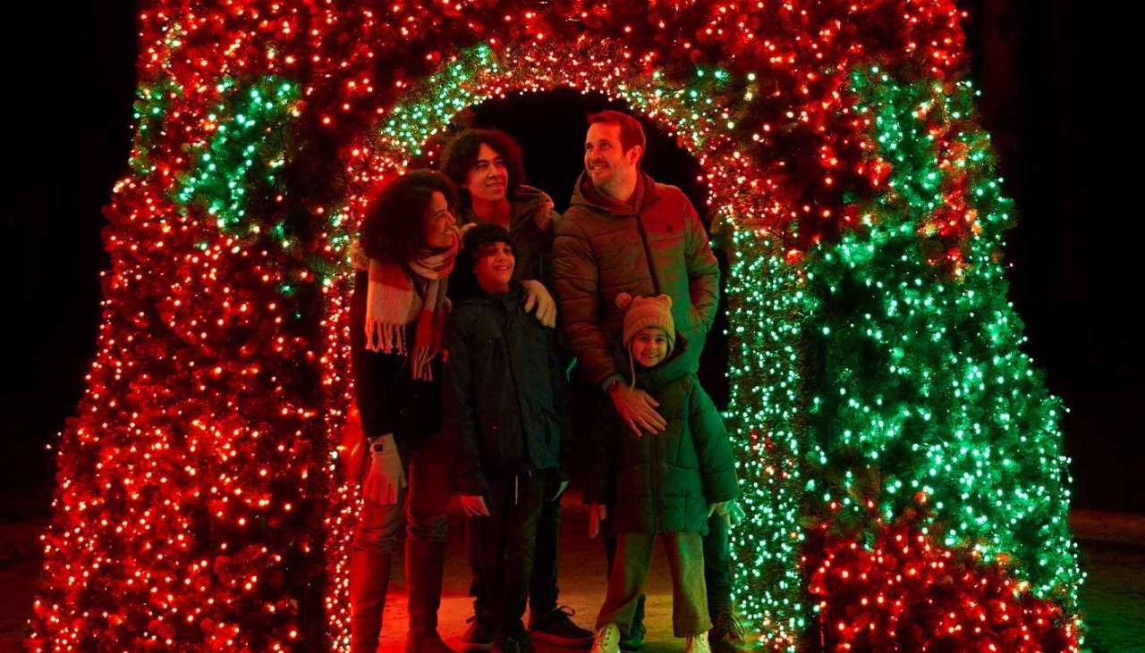 A family posing under an archway made of lights.