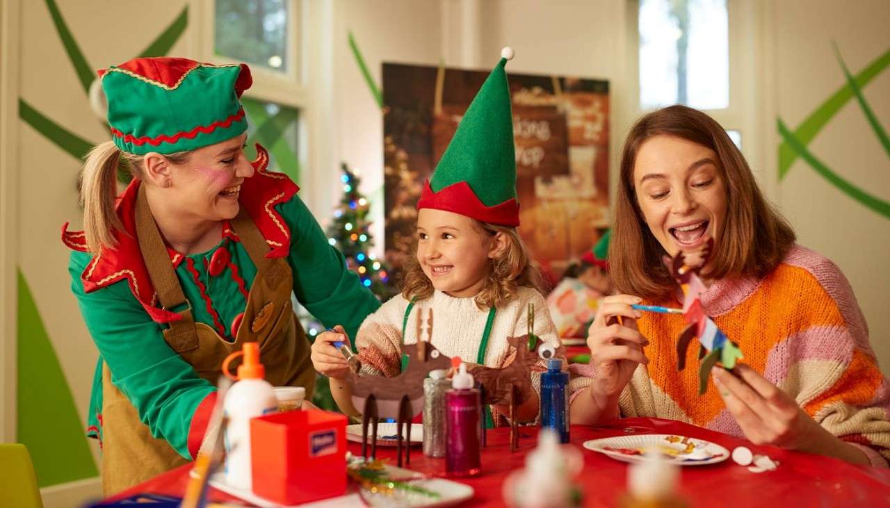 An elf teaching a little girl and her mother how to decorate Christmas toys.
