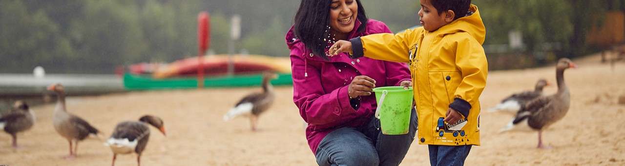 Mother and son feeding ducks on the beach