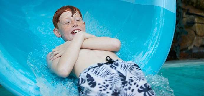 Boy going down a slide into the pool