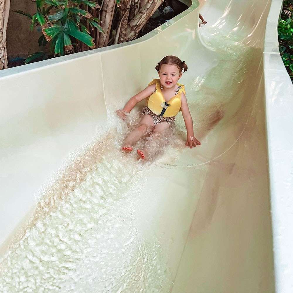 A little boy on a Mini Jet Ski with his dad by his side in the Subtropical Swimming Paradise. 