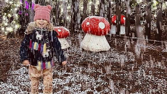 A girl playing in the snow in front of toadstools