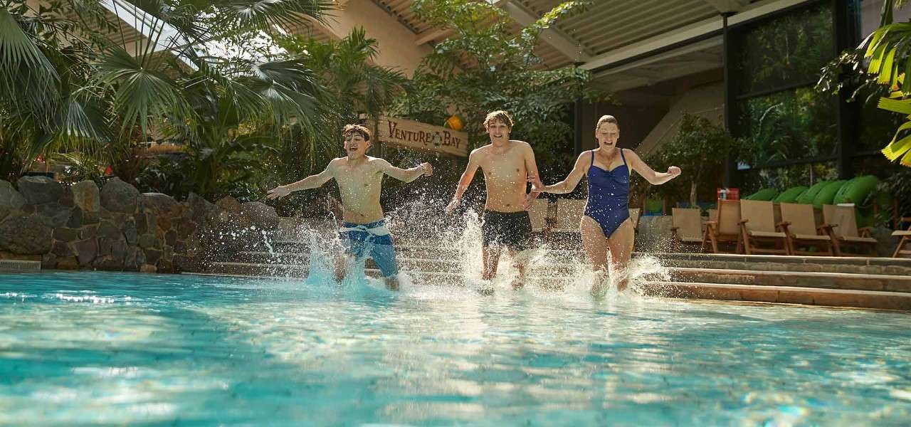 Two teenage boys running in to the Subtropical Swimming Paradise with their mum.