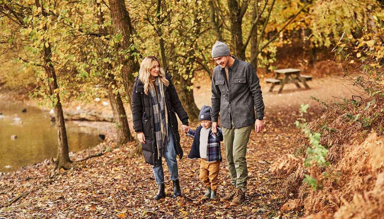 A mum and dad walking through the autumnal forest.