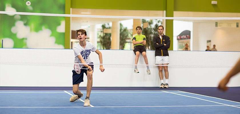 A boy playing badminton on the indoor badminton courts.