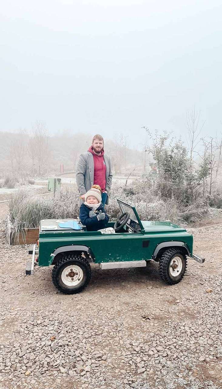 A little boy driving a mini truck in the snow.