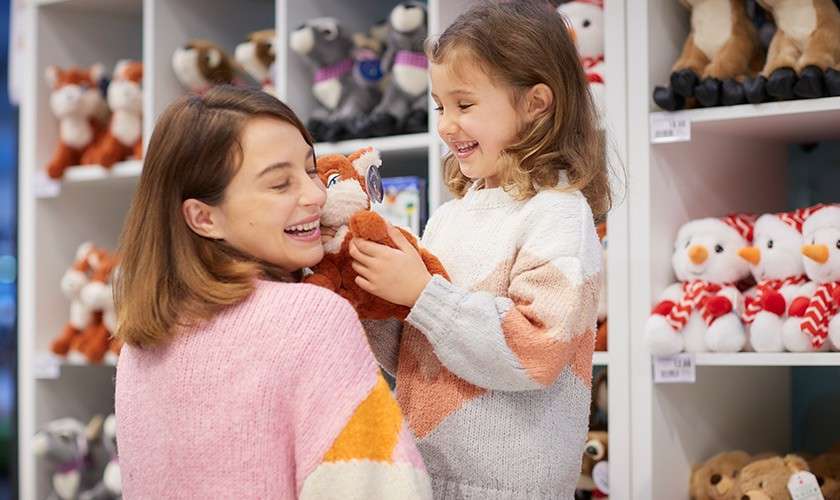 A girl presses her toy against her mums cheek in the festive shop