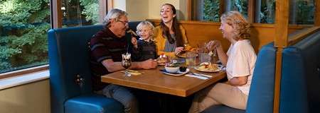 A family sat at a booth in a restaurant eating pancakes.