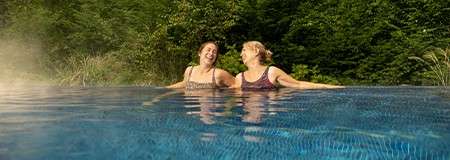 Two women relaxing in an outdoor pool at Aqua Sana spa.