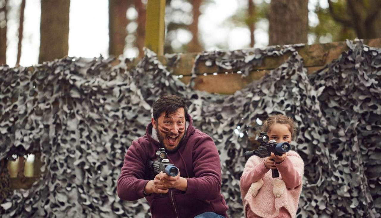 Father and daughter aiming their laser guns in laser combat.