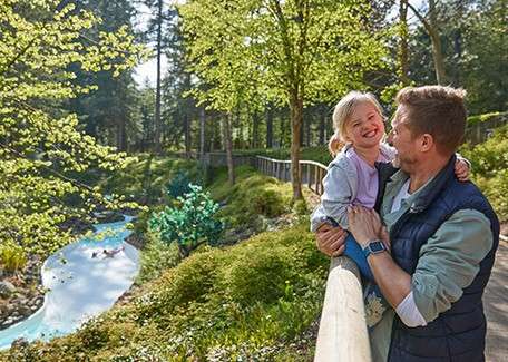 A father holding his daughter overlooking the forest