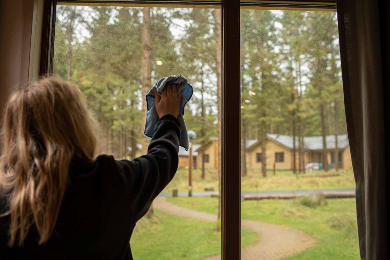 A housekeeper cleaning a lodge window