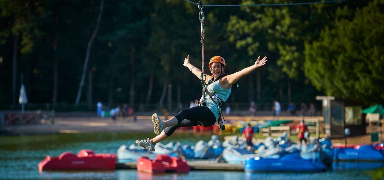 A woman on the zip wire over the lake on Aerial Adventure.
