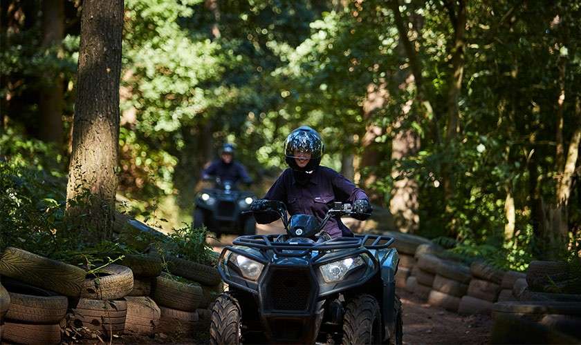 A girl on the Junior Quad bikes going through the forest.