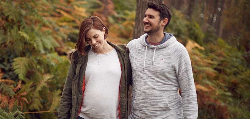Pregnant couple walking through the forest
