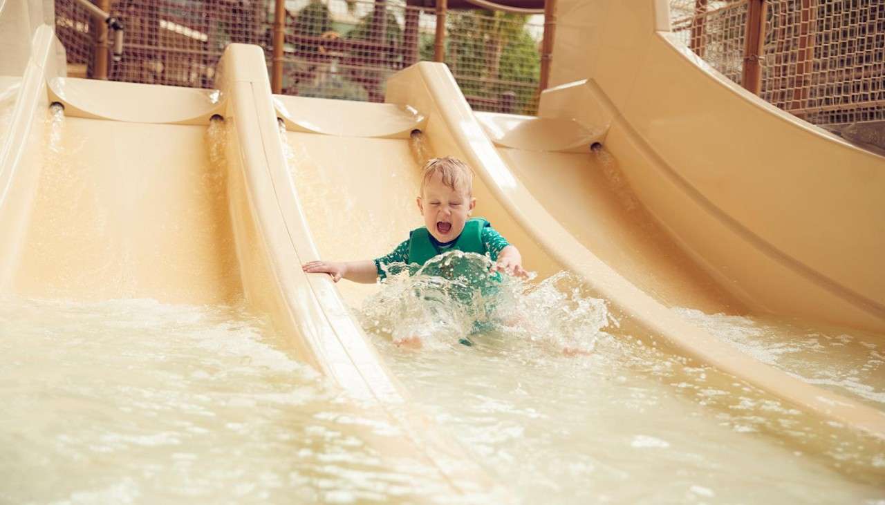 A toddler sliding down a water slide