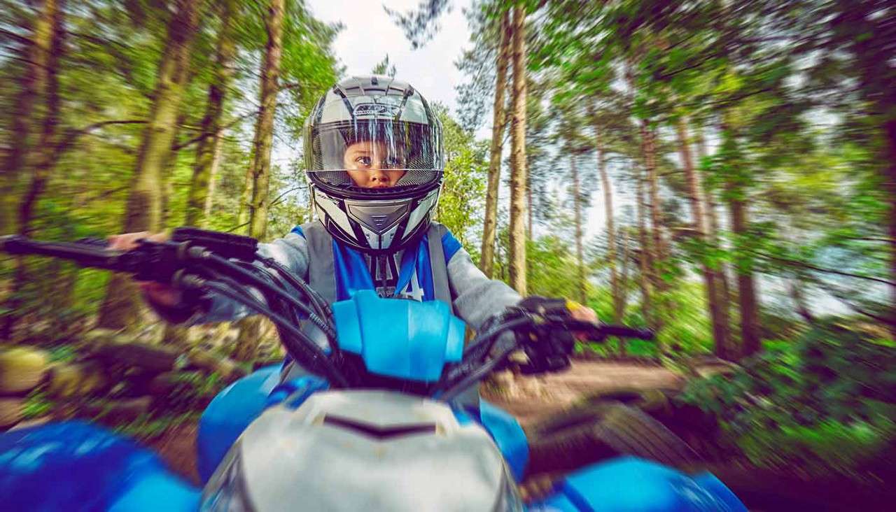 A boy exploring the woodland on a quad bike.