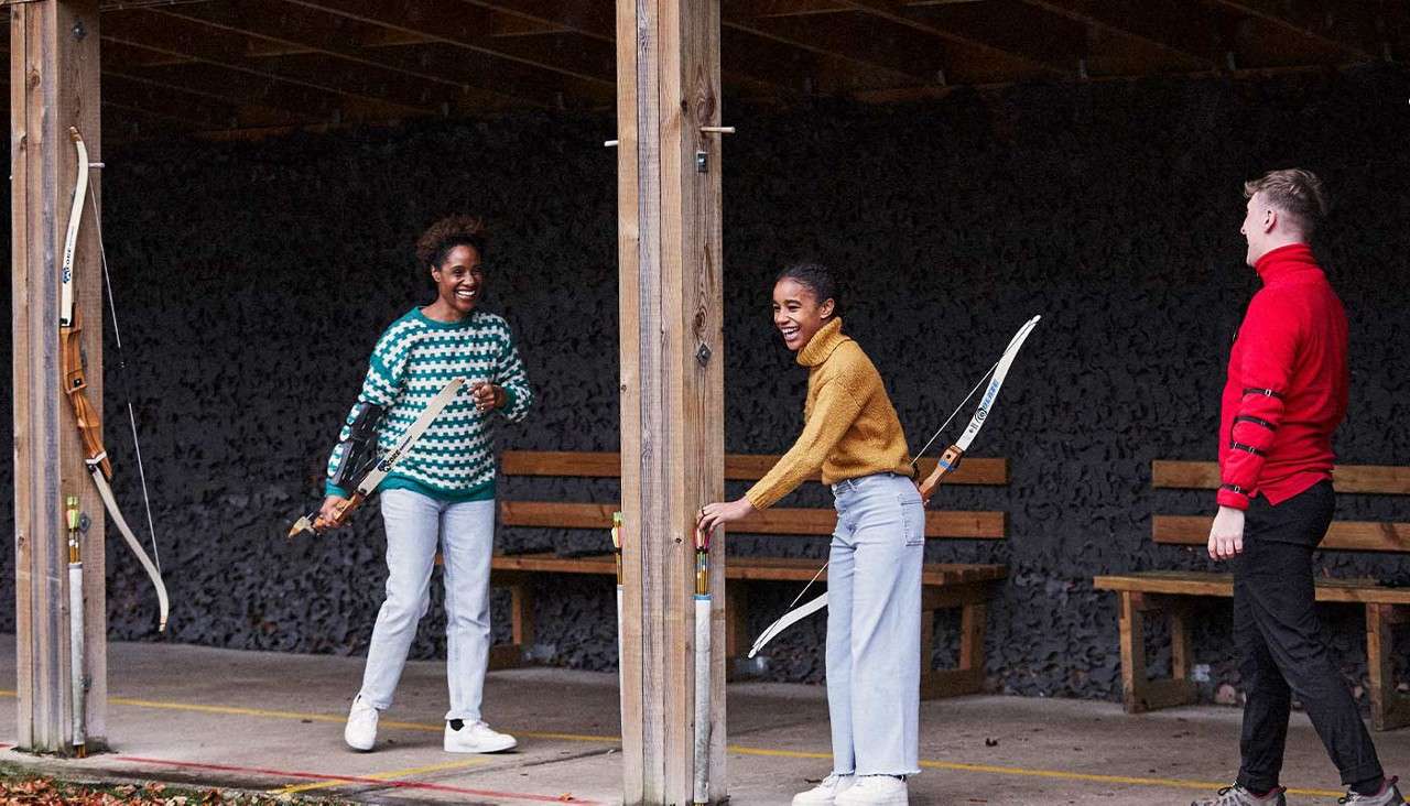 A mum and daughter laugh as they play archery