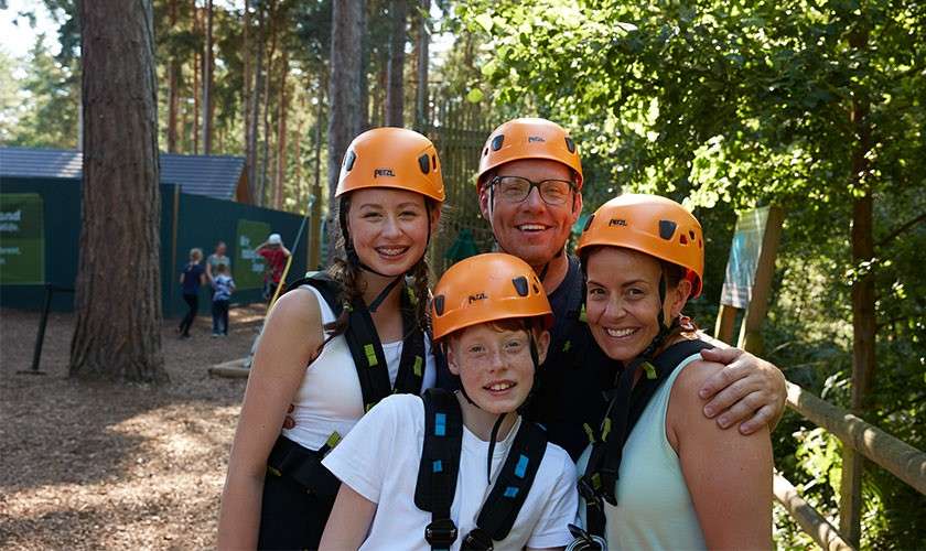A family smiling together for a photo with their helmets on from Aerial Adventure.
