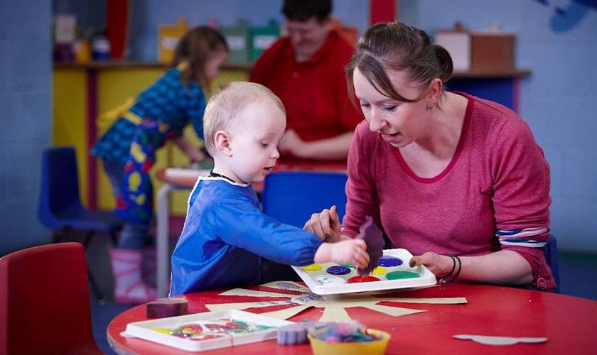 A toddler doing painting in Mucky Pups activity.