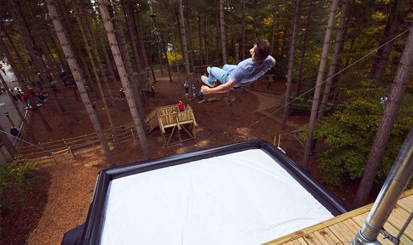 A man jumping off onto an inflatable square.