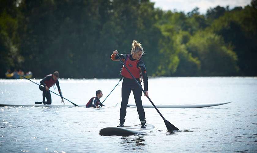 A woman balancing on a paddleboard on the lake.