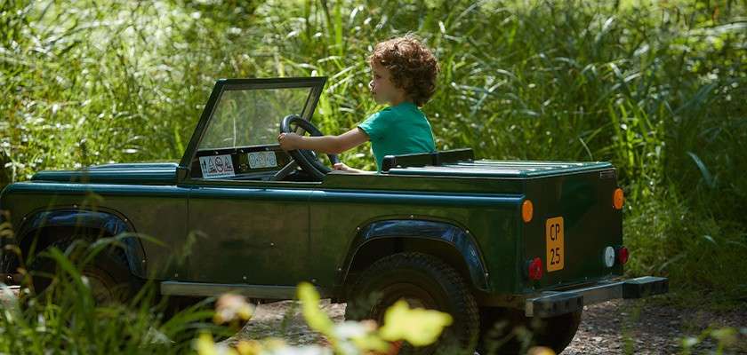 A little boy driving an off road truck.