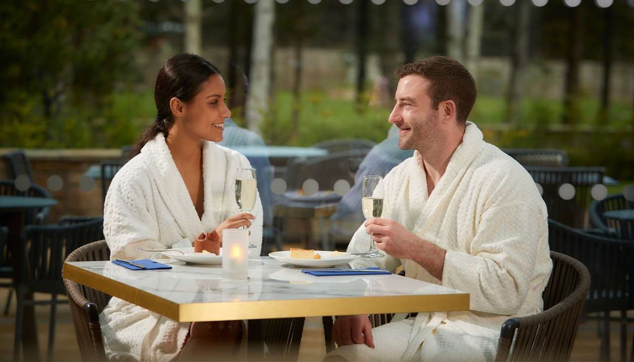 A man and woman sat at Vitale Cafe in their robes with Champagne.