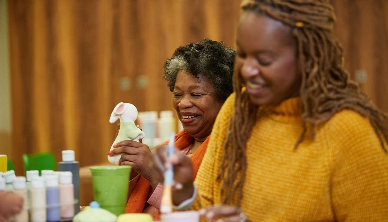 Mother and daughter pottery painting together.