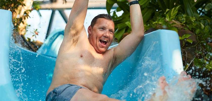 A man smiling while coming down a flume water slide. 