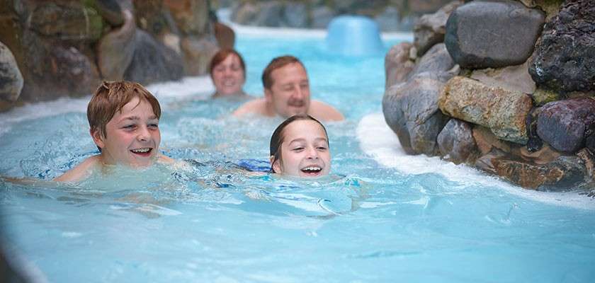 A family on a pool inflatable about to ride the Tropical Cyclone.