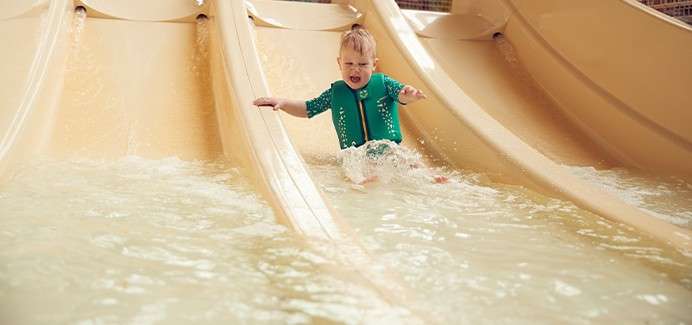 A toddler going down a small waterslide.