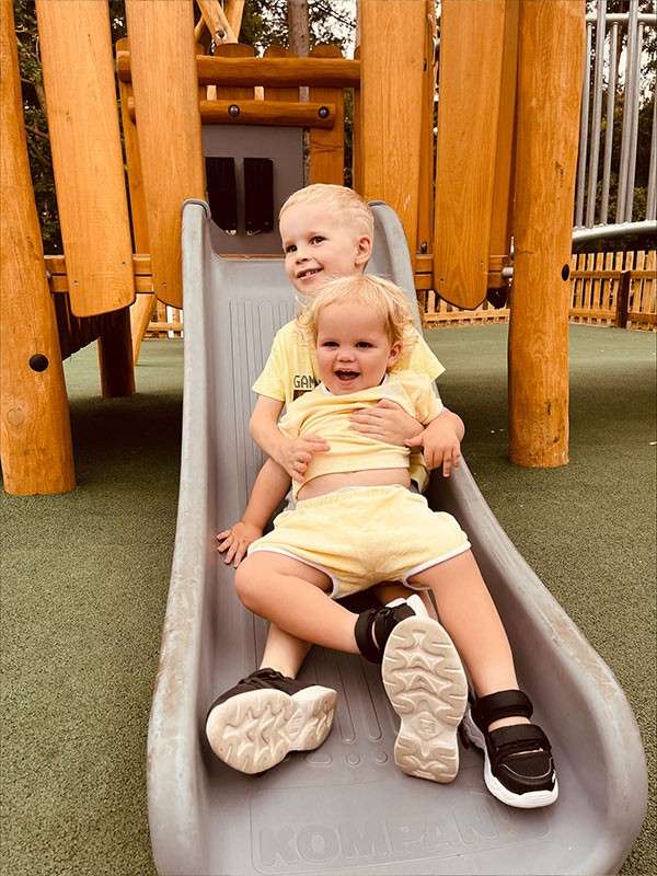 @mummydiarys' image of two children on a slide on the outdoor playground.