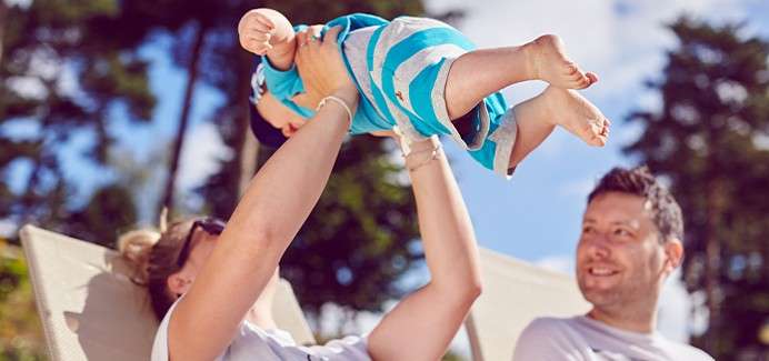 A woman holding her baby up in the air.