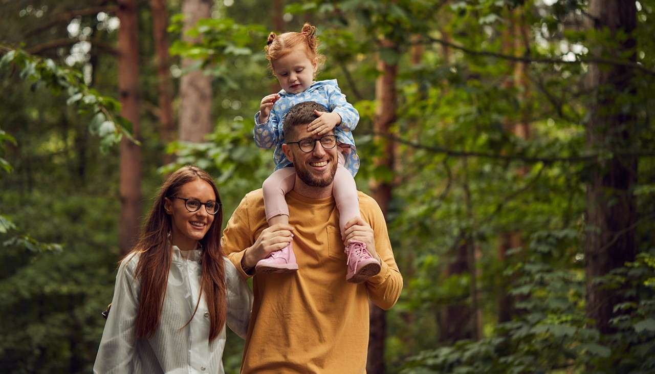 Family walking through the forest with a child on fathers shoulders.