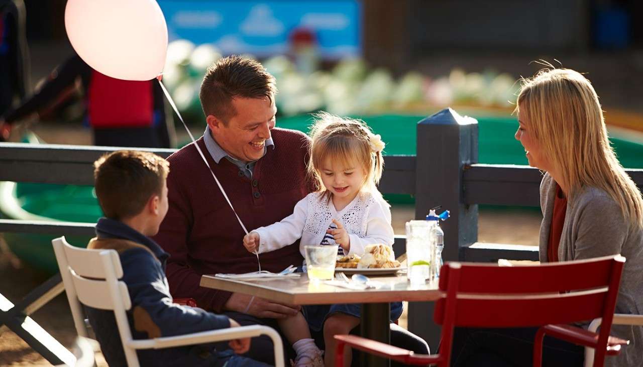 Family eating outside with little girl holding a balloon.