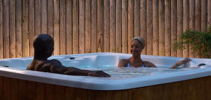 A couple relaxing in a hot tub outside their lodge.