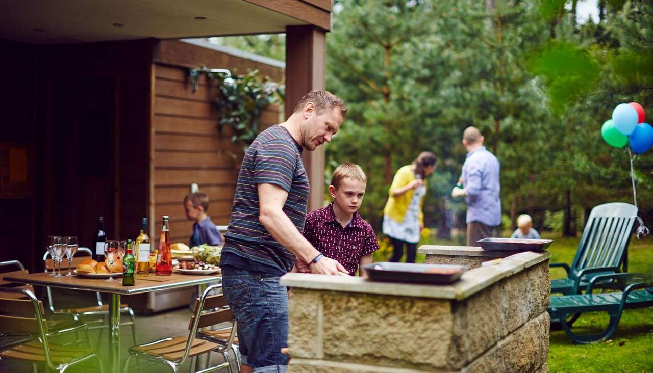 A large family barbecueing outside their lodge