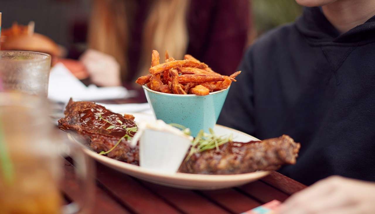 A plate of ribs and sweet potato fries at a restaurant 