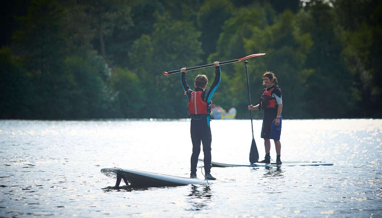 Two people paddleboarding next to each other on the lake 